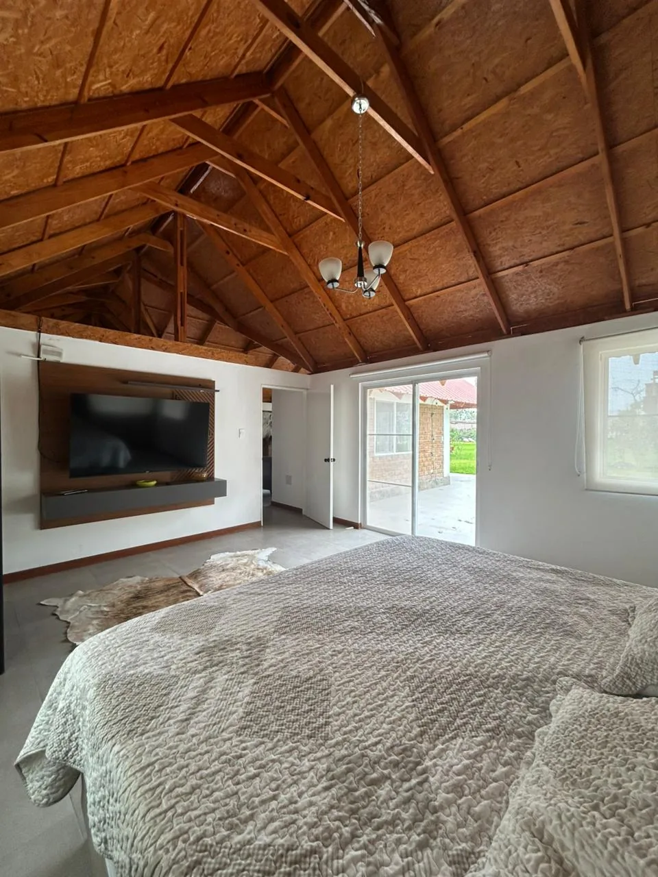 Dormitorio principal con cama king size y techo de vigas de madera — bungalow Cinco Olivos